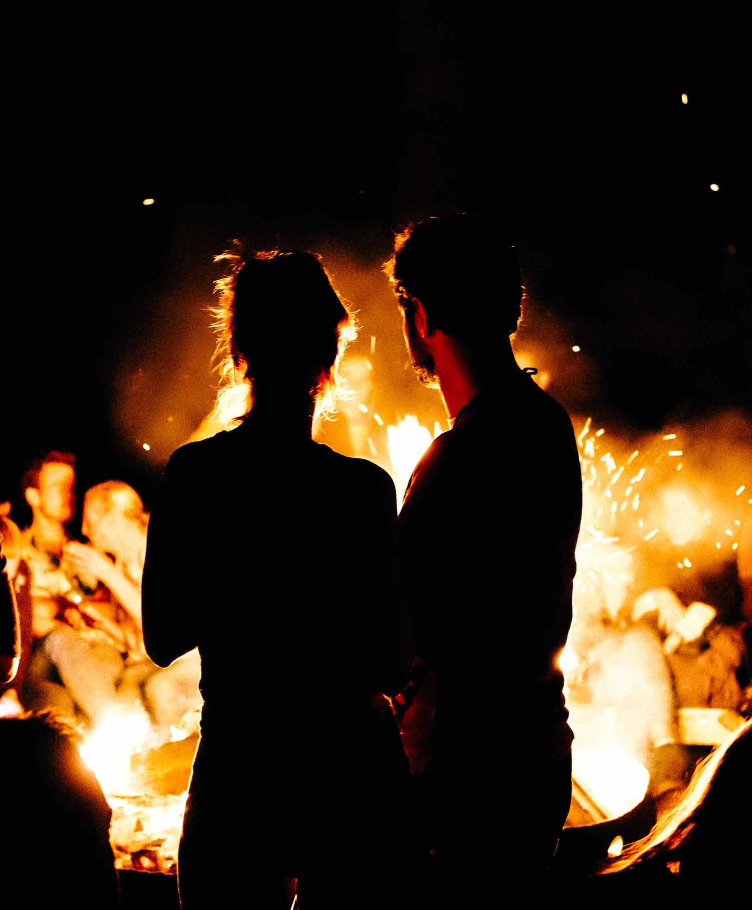 a couple of people standing in front of a fire